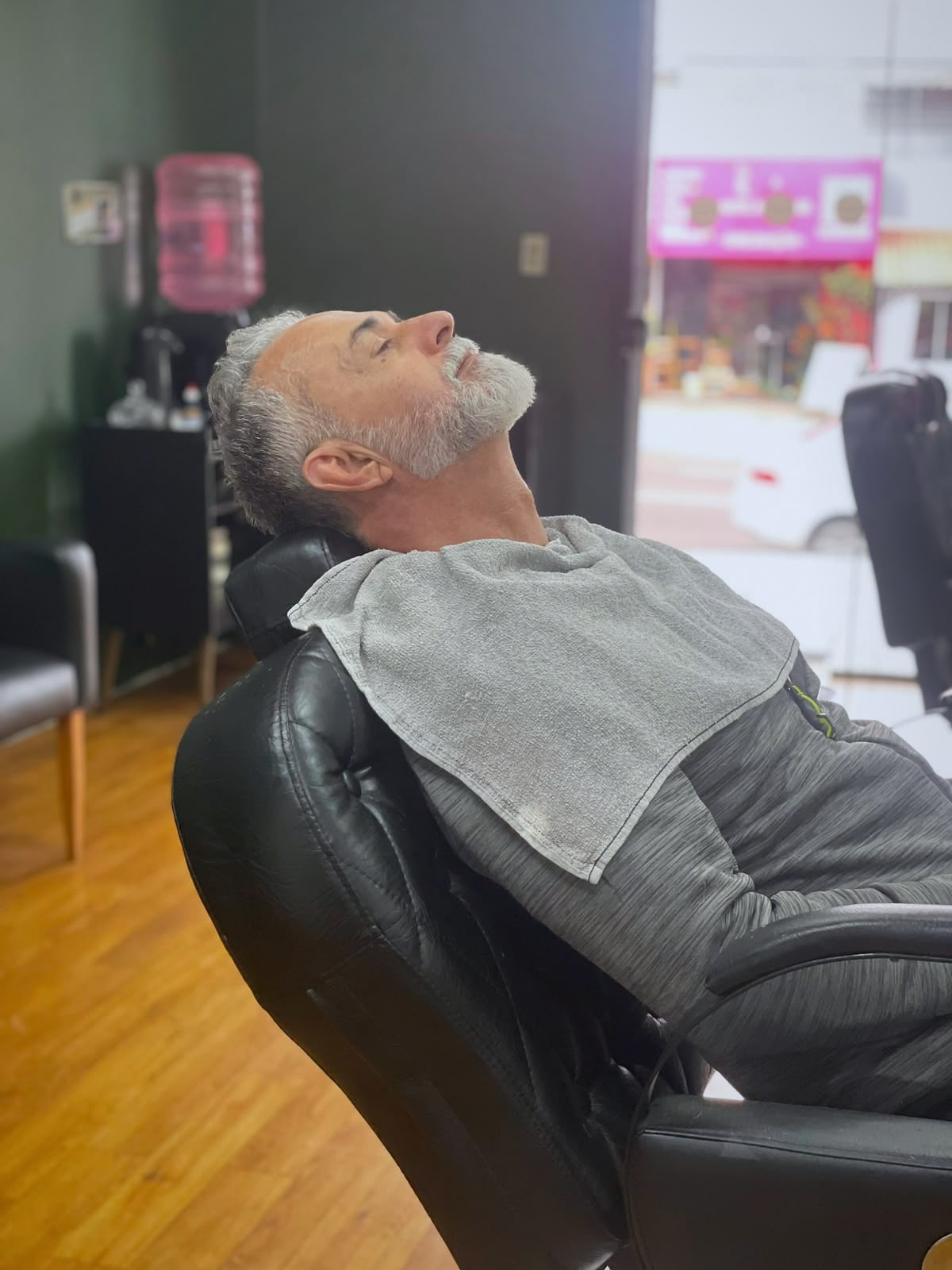 Cliente reclinado na cadeira da Barbearia Ribas, relaxado, com a barba finalizada