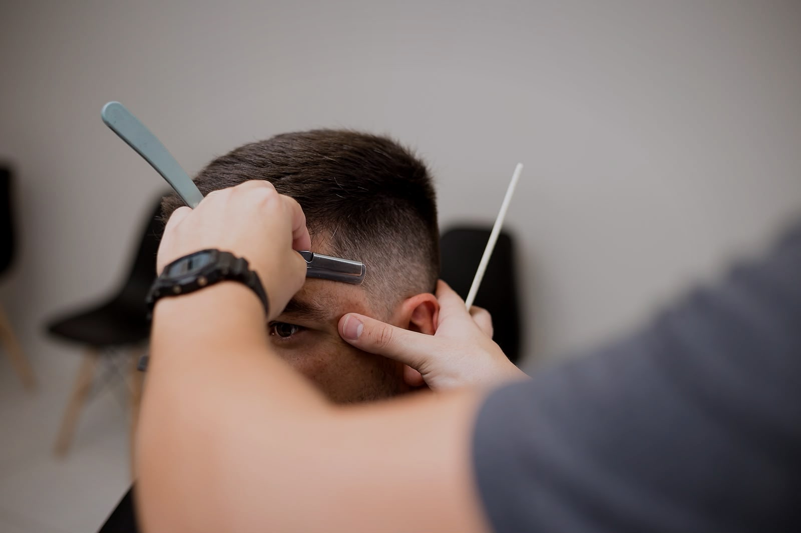 Navalha desenhando o contorno do corte junto à têmpora, na Barbearia Ribas