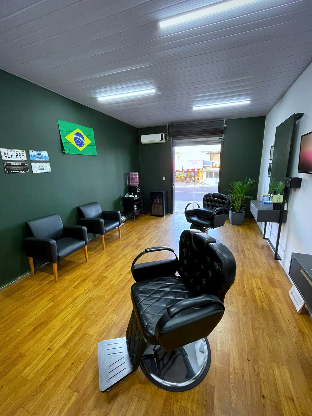 Vista da cadeira principal da Barbearia Ribas em direção à entrada aberta para a rua