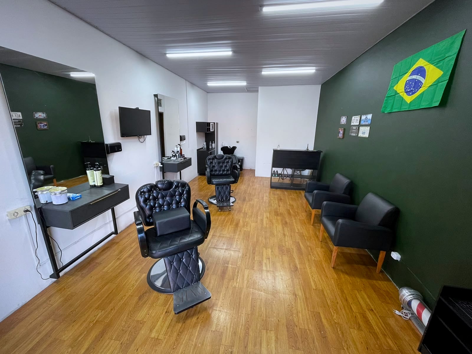 Salão da Barbearia Ribas visto de dentro: parede verde, duas cadeiras de barbeiro pretas, espelhos e poltronas de espera