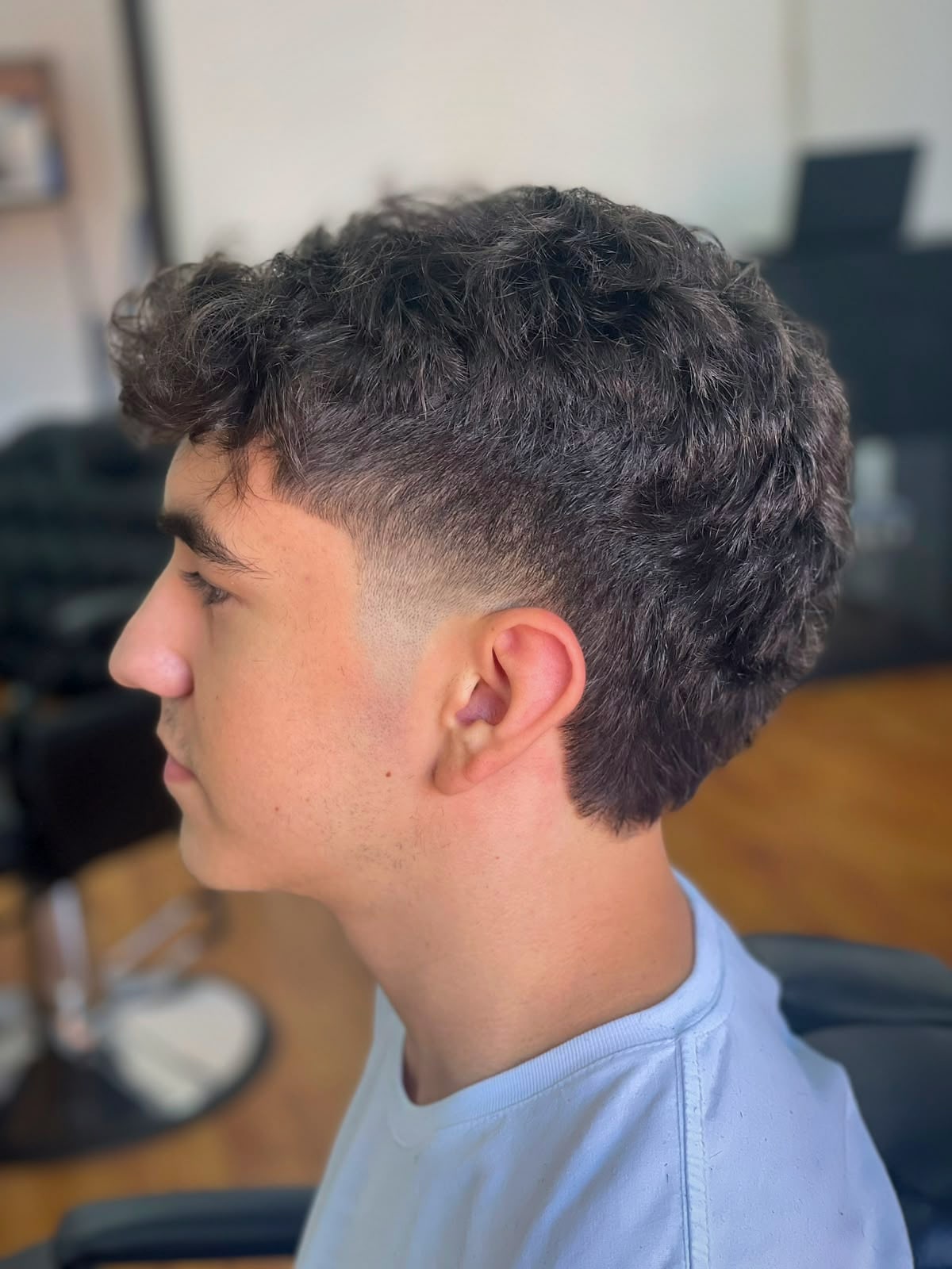 Cliente de perfil na Barbearia Ribas com o cabelo cacheado finalizado após tratamento